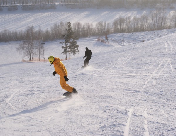 Желтая сноубордистка катится вниз
